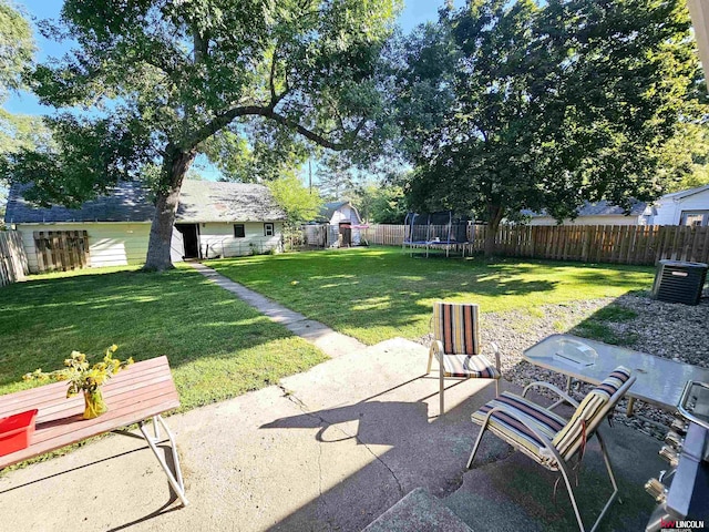 view of yard featuring a patio, a trampoline, a fenced backyard, and an outdoor structure
