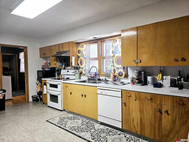 kitchen with under cabinet range hood, light floors, light countertops, white appliances, and a sink