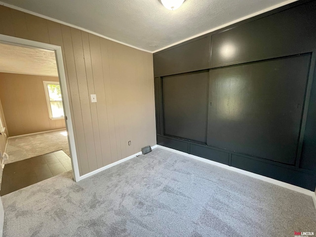 unfurnished bedroom with a textured ceiling, crown molding, carpet, and a closet