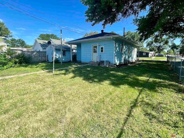 rear view of property featuring a storage shed, a lawn, and central air condition unit