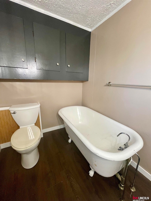 bathroom featuring hardwood / wood-style flooring, crown molding, a tub to relax in, toilet, and a textured ceiling