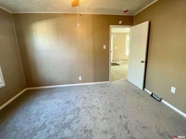 carpeted spare room featuring a textured ceiling, ceiling fan, and wood walls