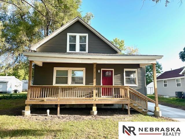 view of front of property with a front lawn, covered porch, and central air condition unit