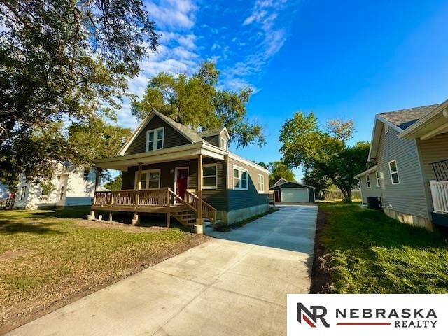 bungalow-style home featuring covered porch, an outbuilding, a front yard, and a garage