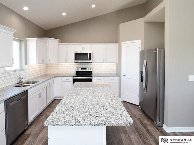 kitchen with a sink, a kitchen island, stainless steel appliances, dark wood-style flooring, and vaulted ceiling