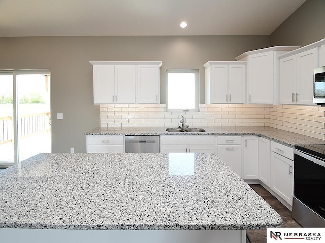 kitchen with light stone counters, backsplash, stainless steel appliances, and a sink