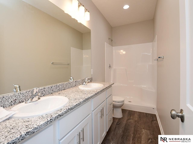 full bathroom with wood finished floors, toilet, walk in shower, and a sink