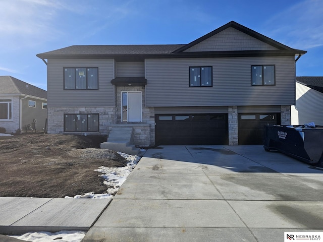 view of front of house featuring stone siding, a garage, and driveway