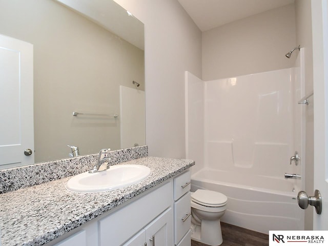 bathroom featuring wood finished floors, toilet, bathtub / shower combination, and vanity