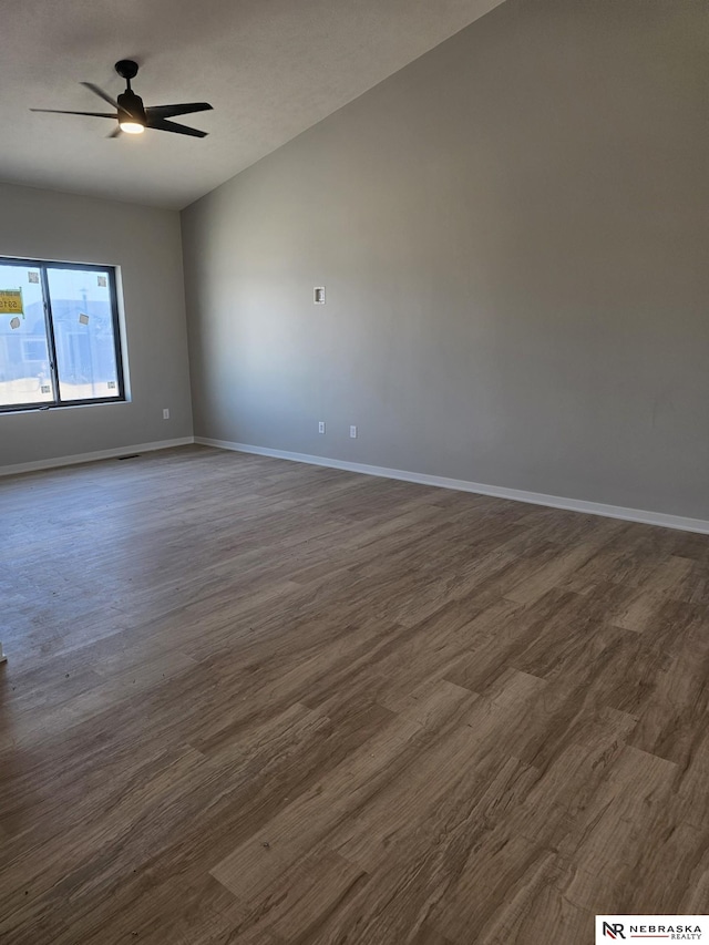 spare room featuring baseboards, dark wood-type flooring, lofted ceiling, and ceiling fan