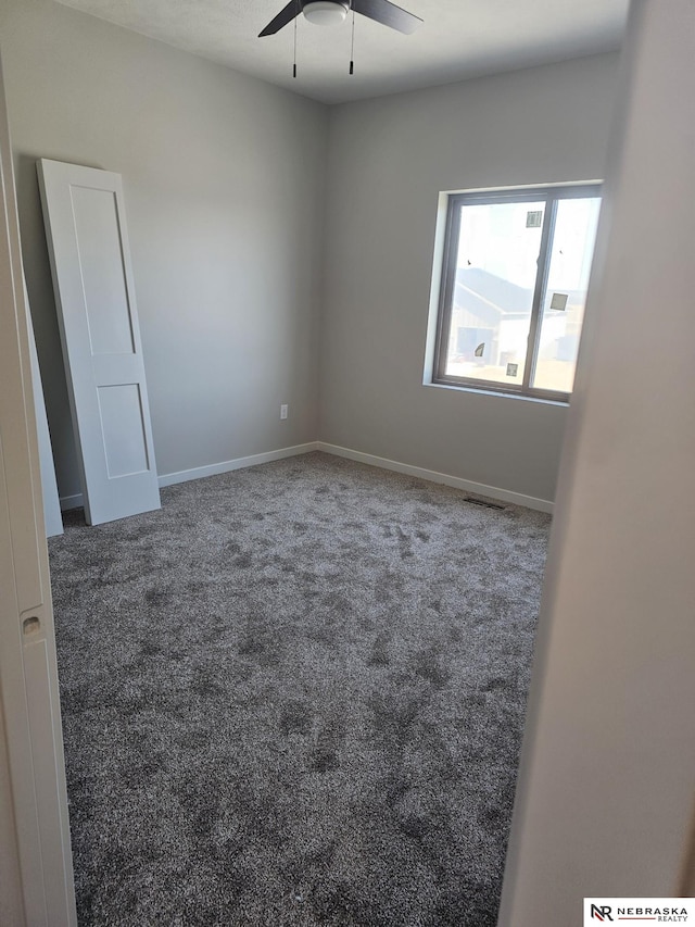 carpeted empty room with visible vents, baseboards, and a ceiling fan