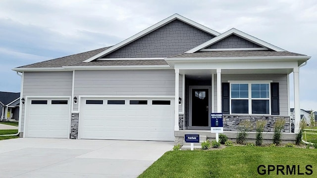 craftsman-style home featuring a garage, a porch, and a front lawn