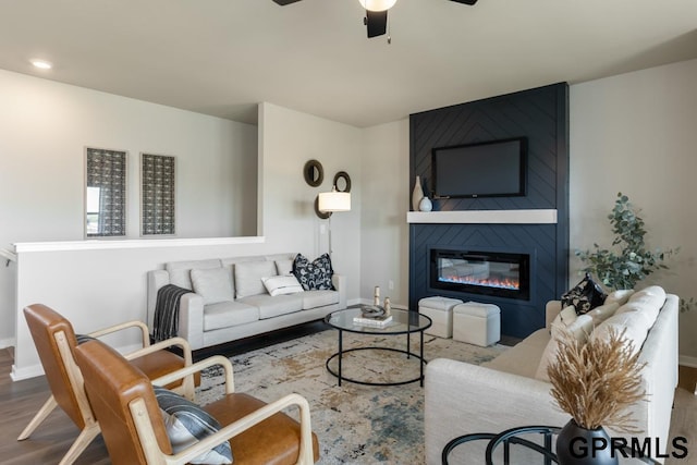 living room featuring hardwood / wood-style floors, ceiling fan, and a fireplace