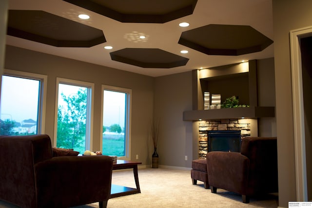 living room featuring a fireplace, a healthy amount of sunlight, a tray ceiling, and carpet