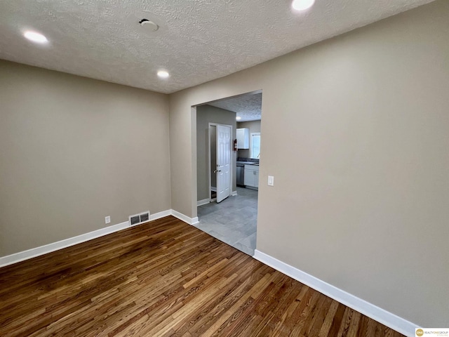 spare room with light wood-type flooring and a textured ceiling