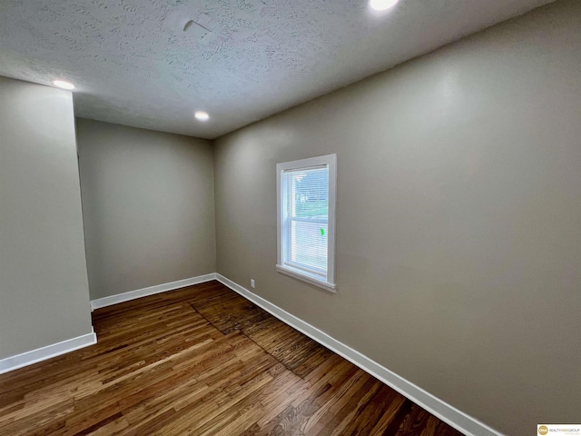 spare room featuring hardwood / wood-style floors and a textured ceiling