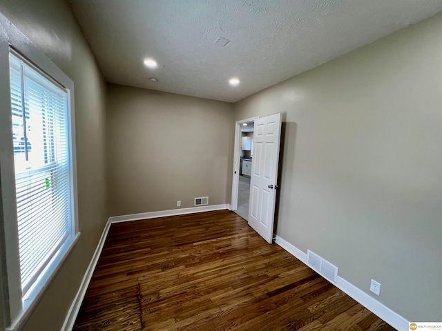 spare room featuring dark wood-type flooring and a textured ceiling