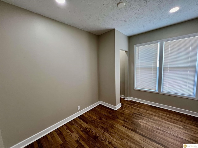 empty room with dark hardwood / wood-style flooring and a textured ceiling