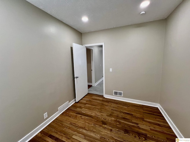 spare room with dark wood-type flooring and a textured ceiling