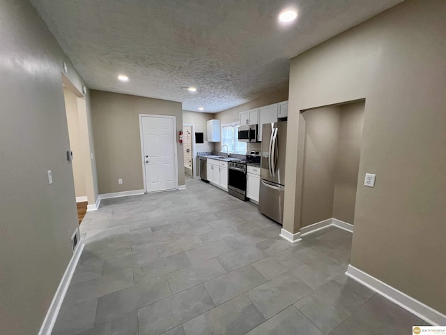 kitchen featuring sink, stainless steel appliances, white cabinetry, and a textured ceiling