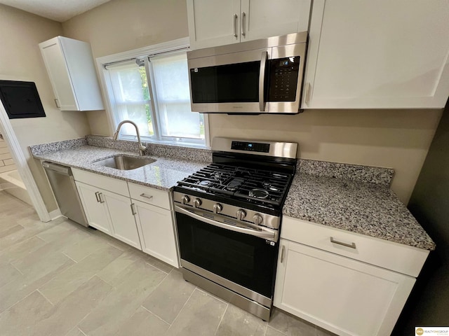 kitchen with sink, light stone countertops, white cabinetry, and stainless steel appliances