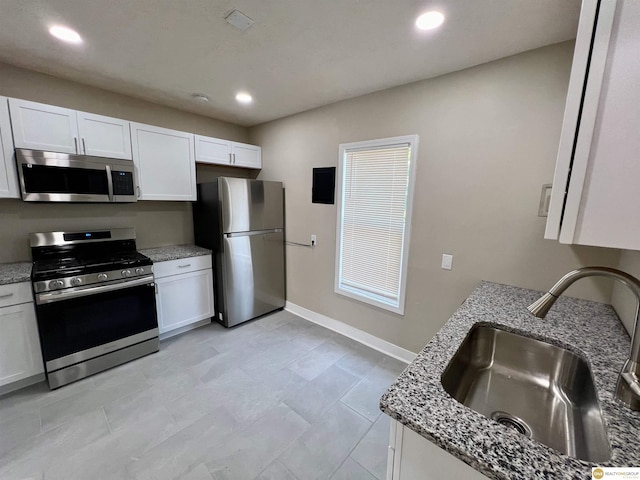 kitchen featuring white cabinetry, sink, stainless steel appliances, and light stone counters