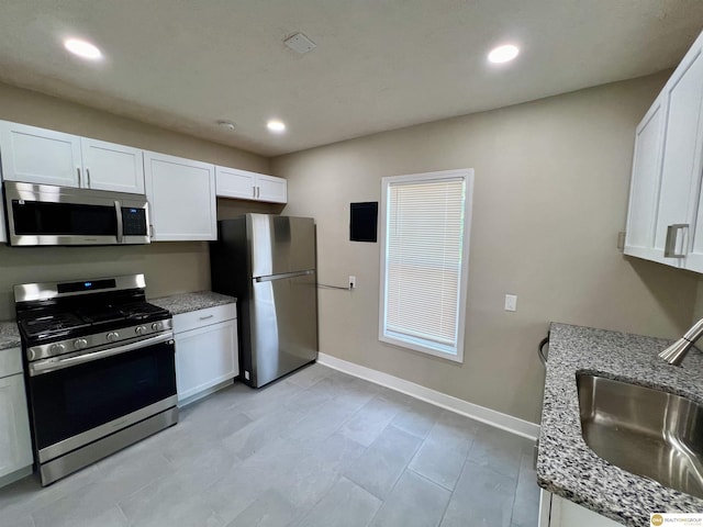 kitchen featuring appliances with stainless steel finishes, sink, white cabinetry, and light stone counters