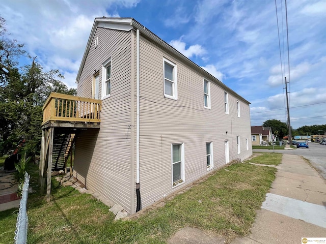 view of side of property featuring a yard and a wooden deck