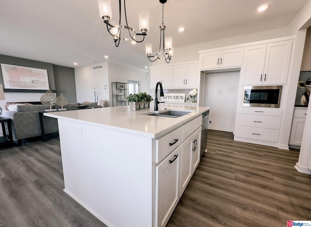 kitchen with a center island with sink, white cabinets, open floor plan, pendant lighting, and a sink