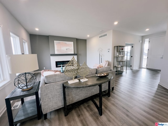 living area featuring recessed lighting, wood finished floors, visible vents, baseboards, and a glass covered fireplace