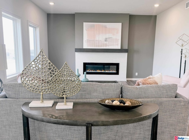 living area featuring wood finished floors, a glass covered fireplace, visible vents, and recessed lighting