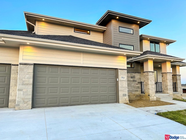 view of front of house featuring a garage, stone siding, and concrete driveway