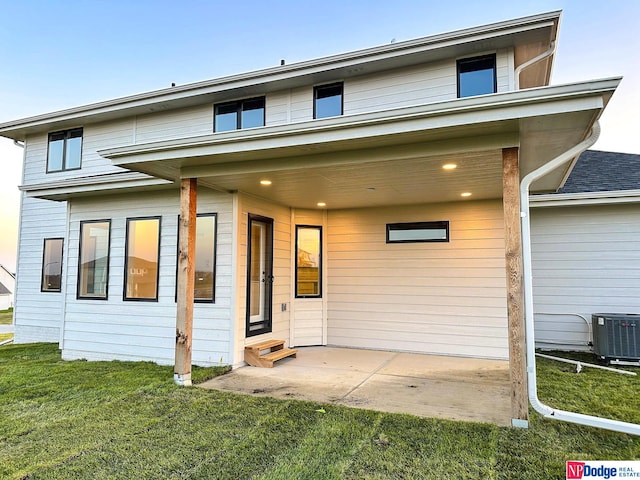 back of house with entry steps, cooling unit, a lawn, and a patio