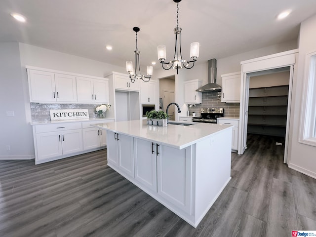 kitchen with light countertops, stainless steel range with electric cooktop, white cabinets, a sink, and wall chimney range hood