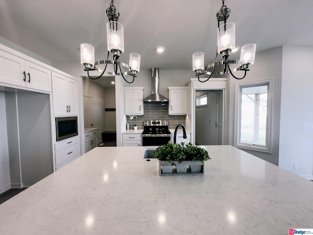 kitchen with light stone countertops, wall chimney exhaust hood, built in microwave, and white cabinets