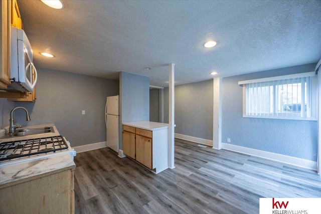 kitchen with white appliances, wood-type flooring, a textured ceiling, and sink