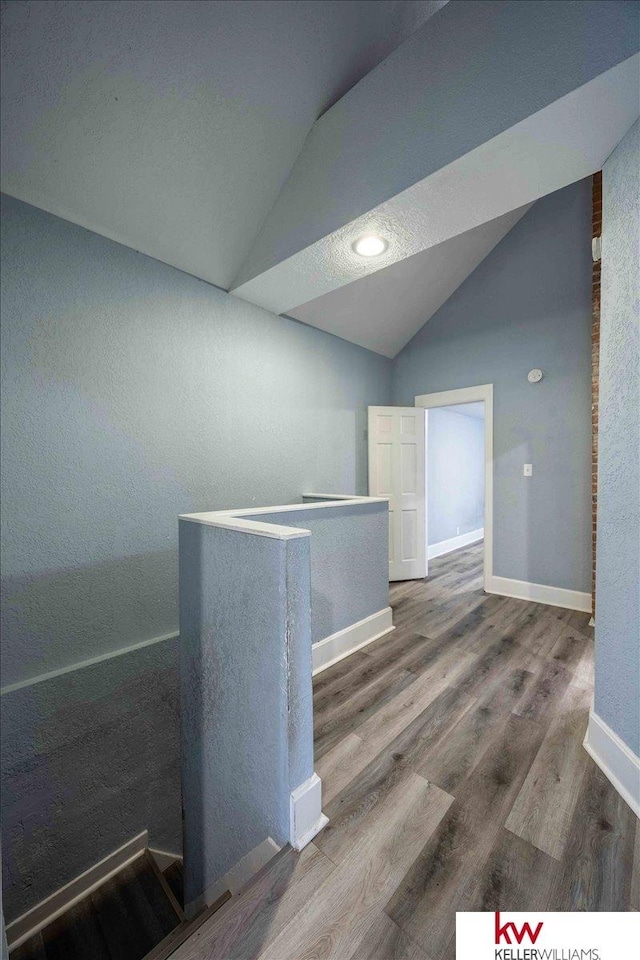 empty room with wood-type flooring and lofted ceiling