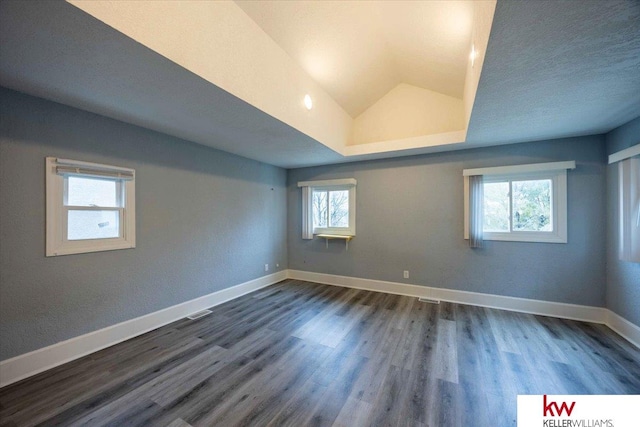 empty room with dark hardwood / wood-style flooring and vaulted ceiling