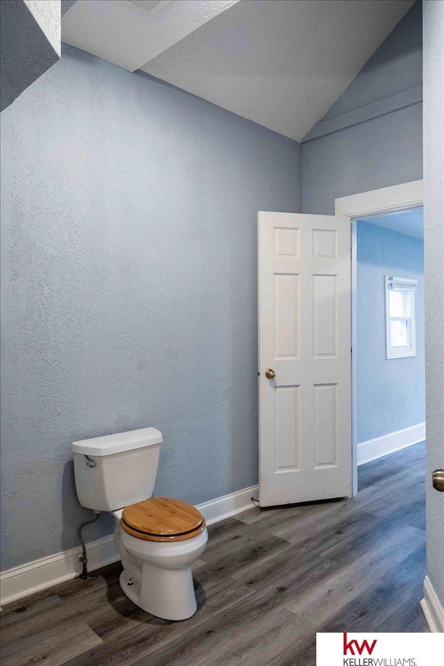 bathroom featuring hardwood / wood-style floors, lofted ceiling, and toilet