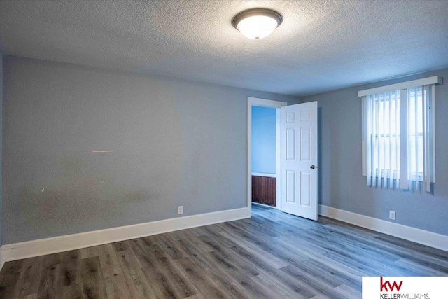 unfurnished room featuring a textured ceiling and dark hardwood / wood-style floors