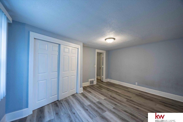 unfurnished bedroom with hardwood / wood-style floors, a textured ceiling, and a closet