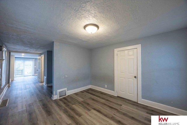 empty room with dark hardwood / wood-style flooring and a textured ceiling