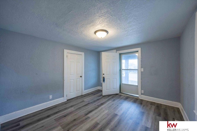 empty room with dark wood-type flooring and a textured ceiling