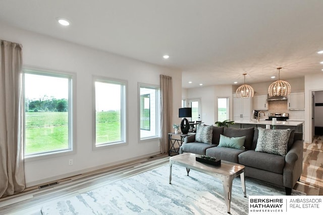 living room featuring sink, an inviting chandelier, and light hardwood / wood-style flooring