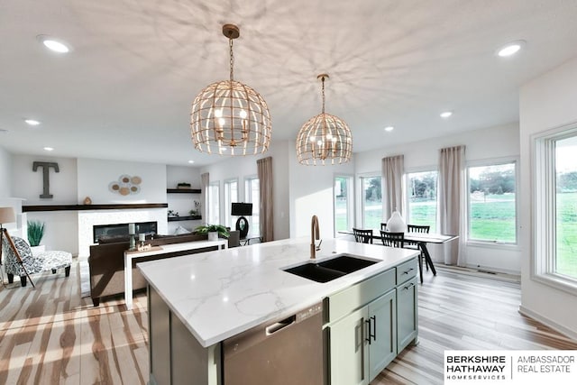 kitchen featuring a notable chandelier, a center island with sink, sink, hanging light fixtures, and stainless steel dishwasher