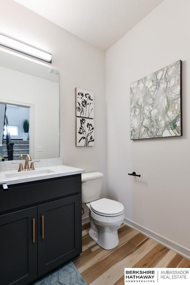 bathroom with vanity, toilet, and hardwood / wood-style flooring