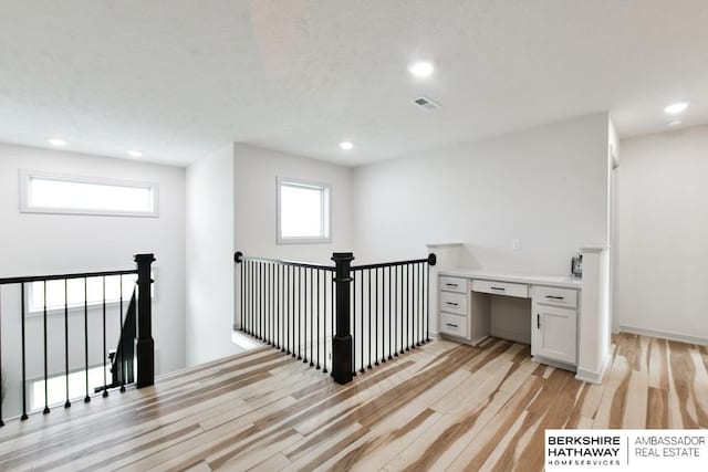 hall with a textured ceiling and light hardwood / wood-style flooring