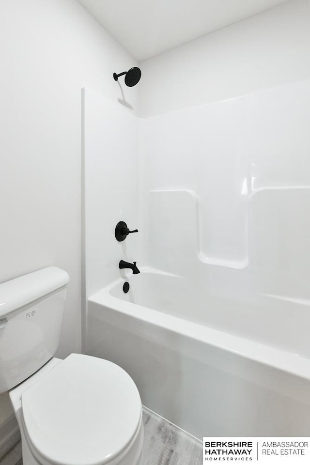 bathroom featuring toilet, hardwood / wood-style flooring, and bathing tub / shower combination