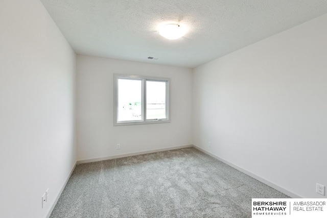 carpeted empty room with a textured ceiling