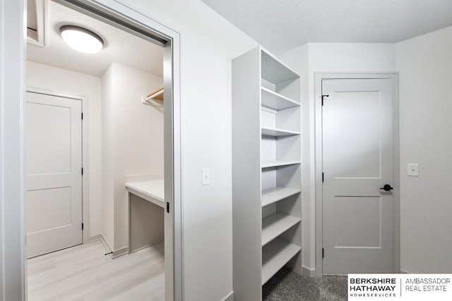 walk in closet with light hardwood / wood-style floors